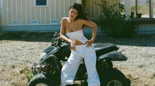 Classic wardrobe staples featuring white pants and a strapless white top styled on an ATV in a casual outdoor scene.
