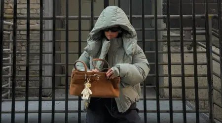 Outerwear for women featuring a hooded puffer jacket styled with sunglasses and a large tan handbag.
