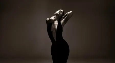 Luxury fabrics for dresses showcased in a dramatic photo of a woman wearing a deep plunge black velvet gown.