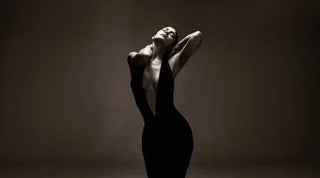 Luxury fabrics for dresses showcased in a dramatic photo of a woman wearing a deep plunge black velvet gown.