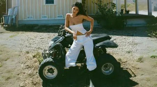 Strapless top styled with white pants as a woman poses on an all-terrain vehicle in a rural setting